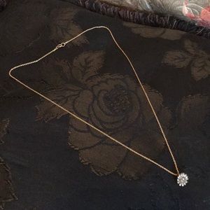 Gold necklace with flower charm.